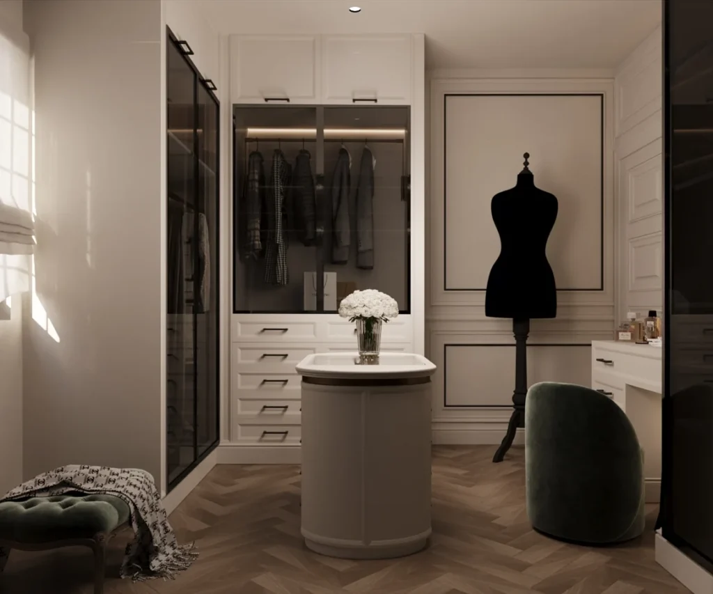 تصميم غرفة ملابس فاخرة (Walk-in Closet) بنمط فرنسي معاصر من تنفيذ تيلا للتصميم الداخلي بالرياض، تضم خزائن زجاجية مضيئة وجزيرة وسطية بيضاء مع أرضية خشبية هيرينغبون.